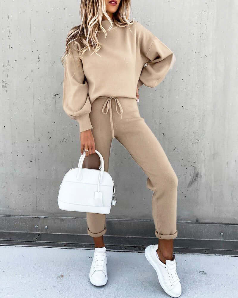 Casual high neck long sleeve beige two-piece suit featuring pocket trousers, styled with white sneakers and handbag.