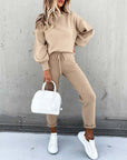 Casual high neck long sleeve beige two-piece suit featuring pocket trousers, styled with white sneakers and handbag.