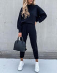 Casual high neck long sleeve black trousers two-piece suit outfit with handbag and white sneakers.