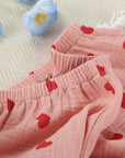 Close-up of soft pink cotton pajamas featuring red heart prints, showcasing comfortable waistband and fabric texture.