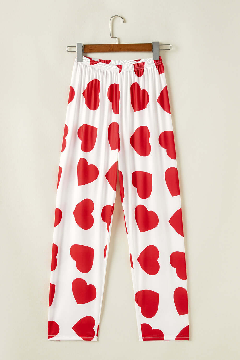 Red heart print lounge pants hanging on a hanger, perfect for women&#39;s pjs from Little Miss Vanilla clothing UK.