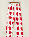 Red heart print lounge pants hanging on a hanger, perfect for women's pjs from Little Miss Vanilla clothing UK.