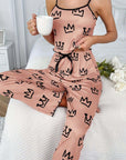 Stylish woman in pink two-piece milk silk suspender pajamas with crown pattern, enjoying coffee at home.