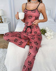 Model wearing pink milk silk suspender pajamas with crown design, holding a mug, in a cozy bedroom setting.