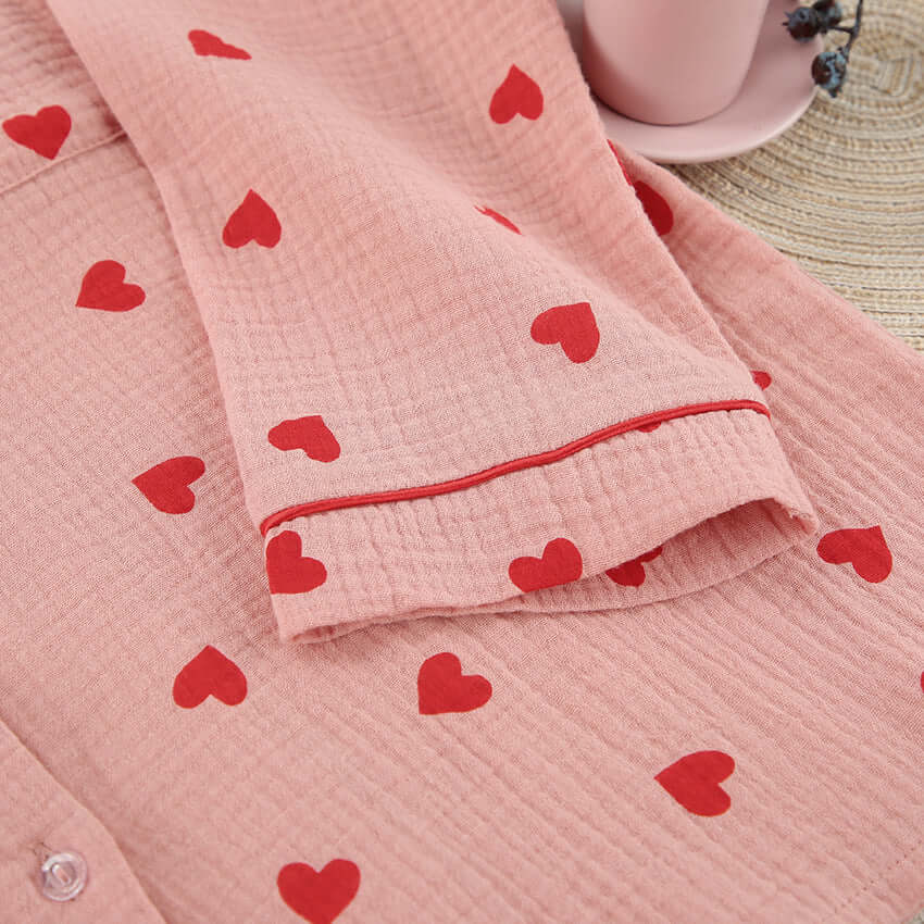 Close-up of soft pink cotton pajama fabric with red heart prints and sleeve detail.