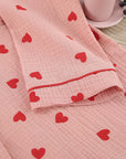 Close-up of soft pink cotton pajama fabric with red heart prints and sleeve detail.